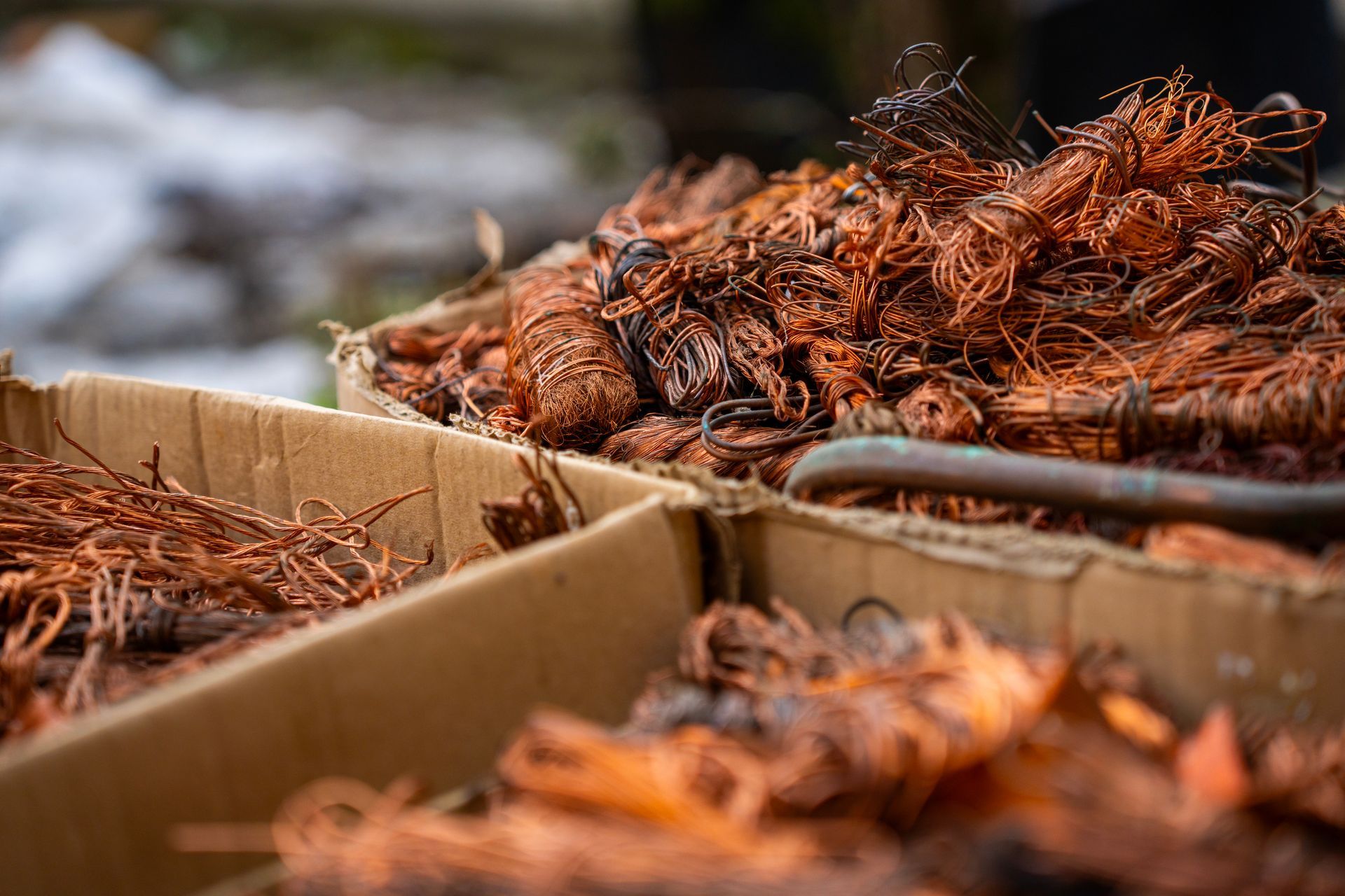 Cardboard boxes filled with tangled copper wire scrap, highlighting metal recycling. Cardboard boxes filled with tangled copper wire scrap, highlighting metal recycling.