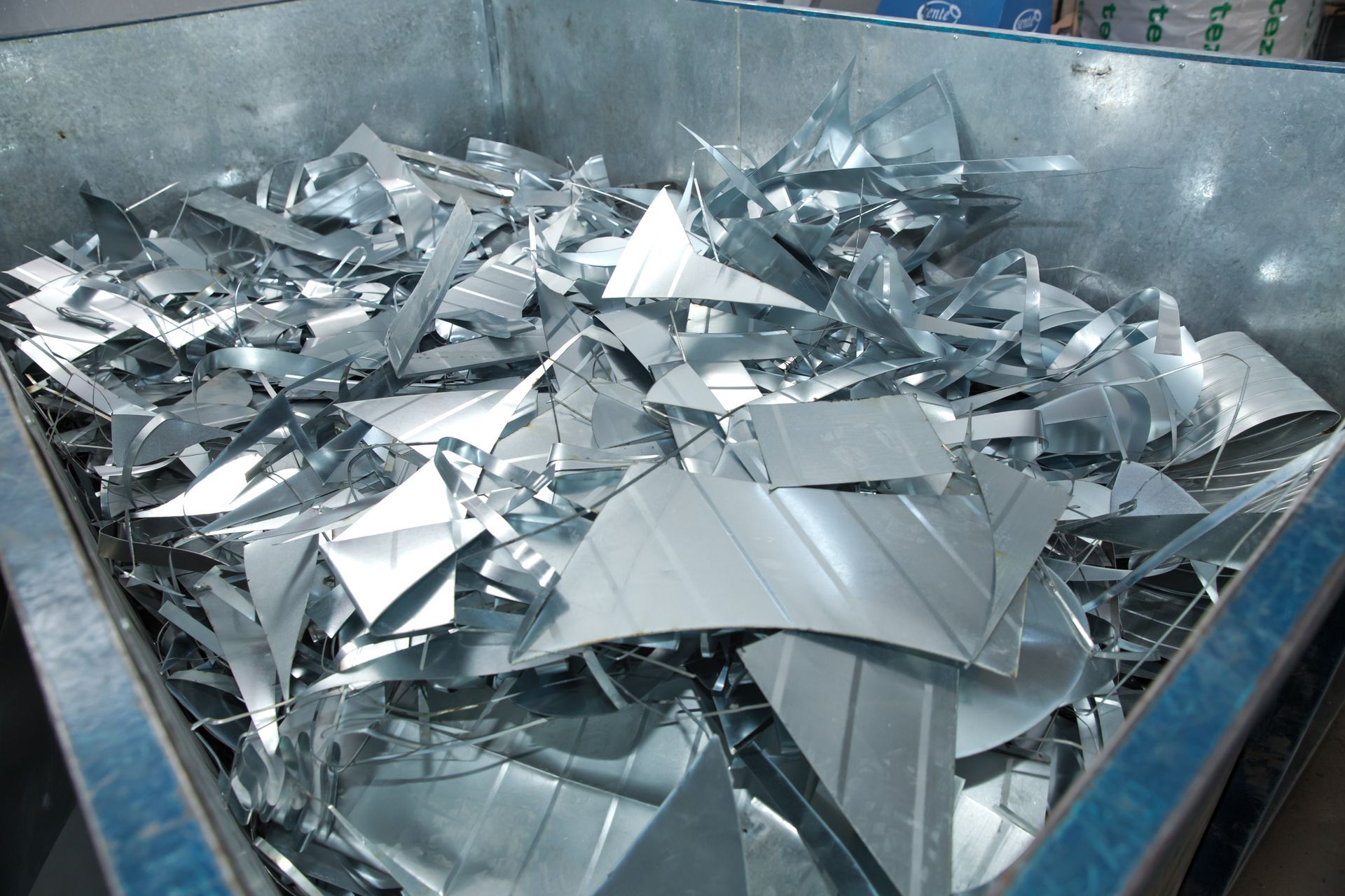 A pile of aluminum scraps inside a blue container. A pile of aluminum scraps inside a blue container.