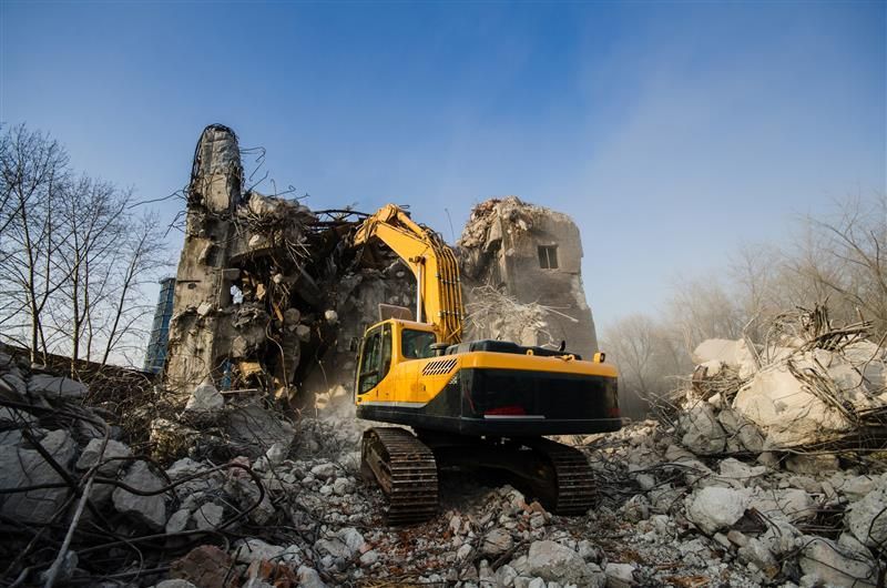 Excavator demolishing large concrete building during professional demolition project.