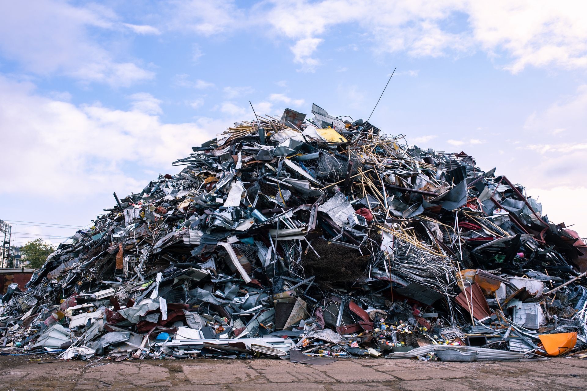 Large pile of scrap metal under blue sky.