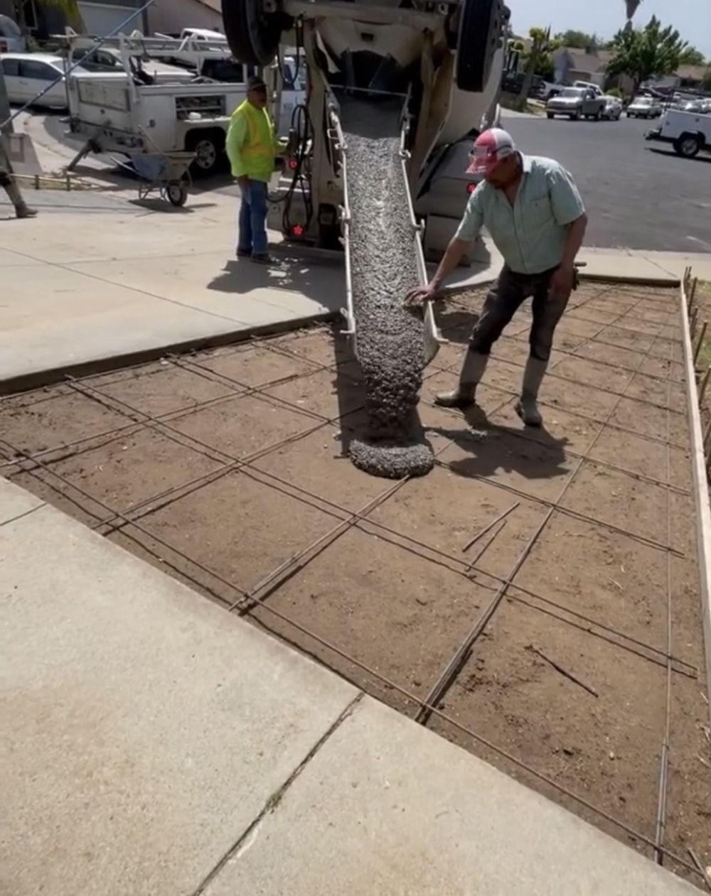 A man is pouring concrete on a sidewalk with a shovel