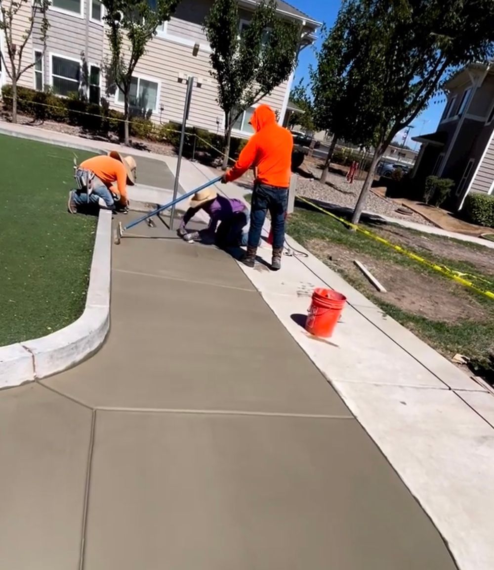 A group of construction workers are working on a sidewalk