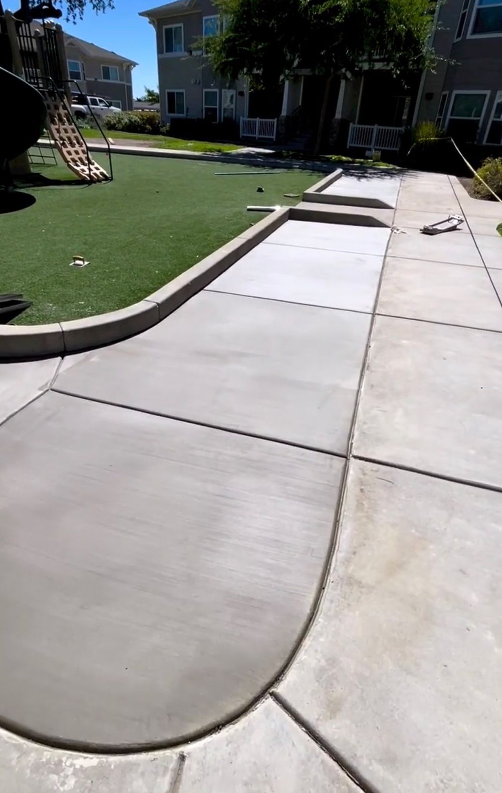 A concrete walkway leading to a playground in a park.