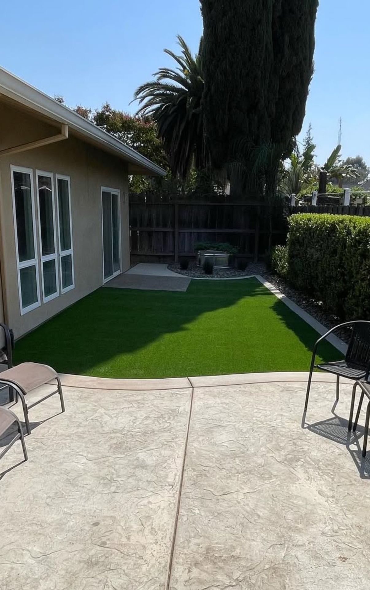 A patio with chairs and a table in front of a house.