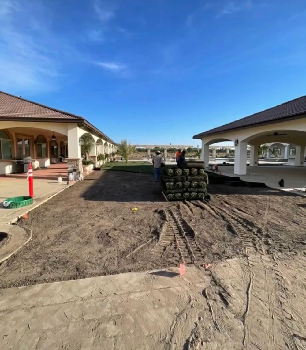 A stack of sod is sitting in the dirt in front of a house