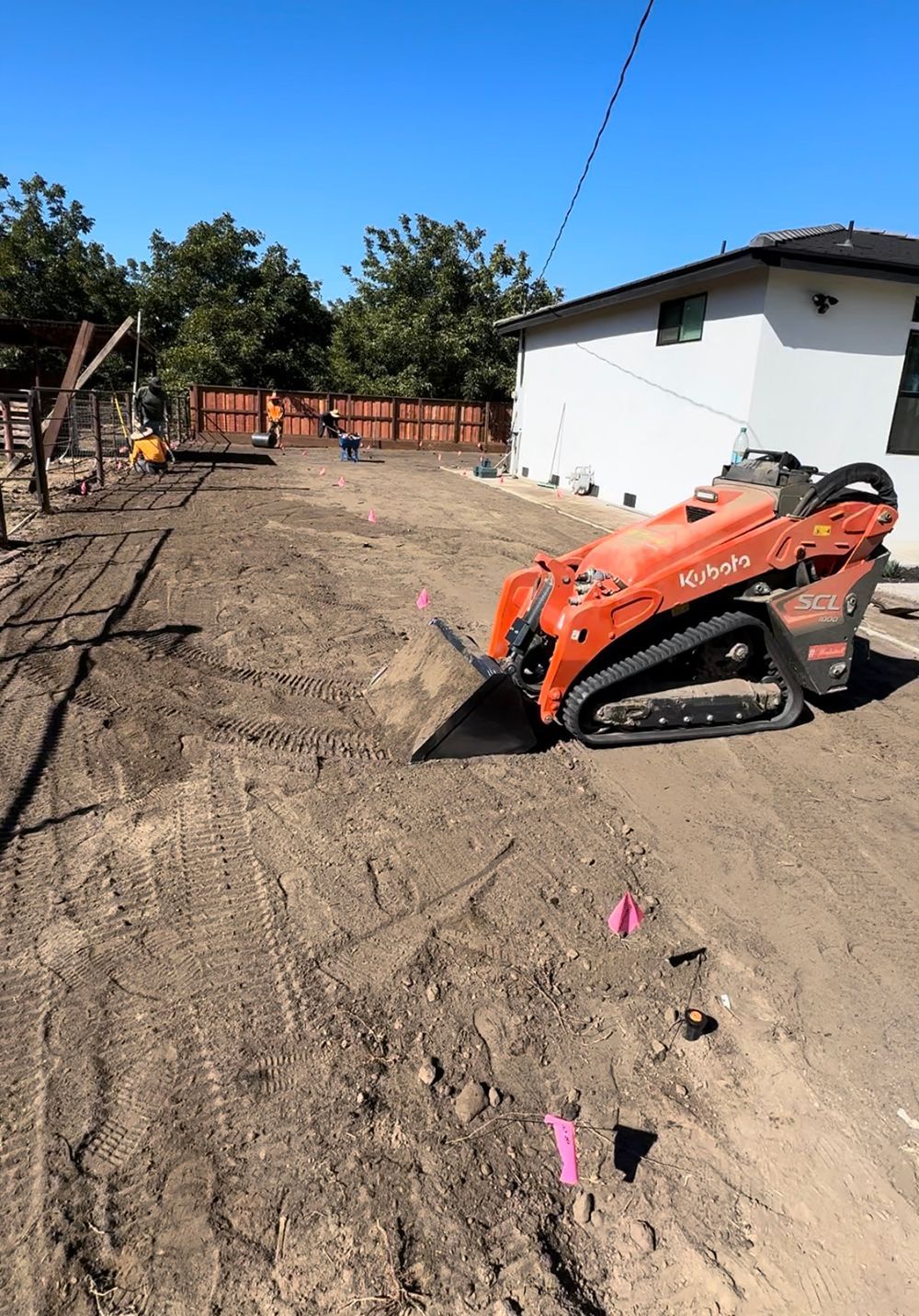 A bulldozer is sitting in the dirt in front of a house.