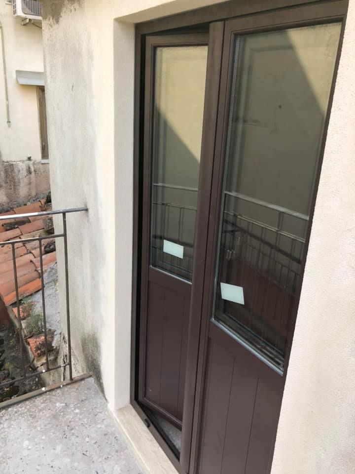 Porta doppia marrone con pannelli in vetro sul balcone.