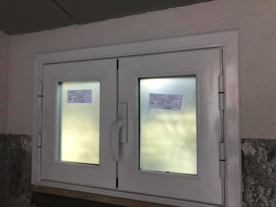 Finestra bianca con doppi vetri smerigliati e maniglia. Due fogli di carta sono attaccati al vetro.