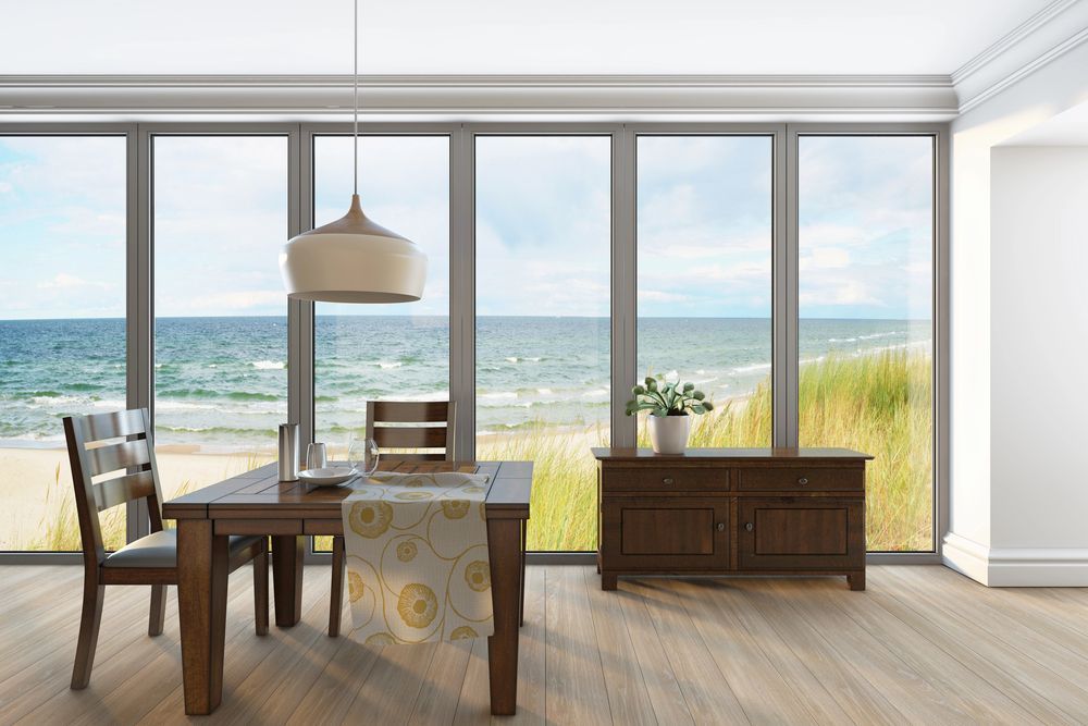 Sala da pranzo con vista sull'oceano, tavolo con sedie, mobile in legno, lampada a sospensione.