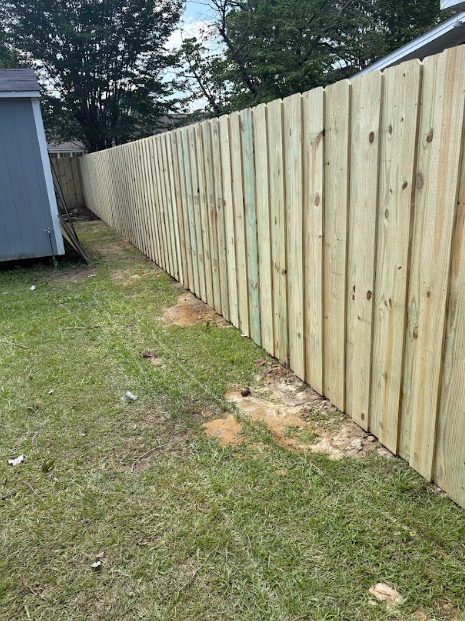 A new, wooden fence alongside a grassy yard.