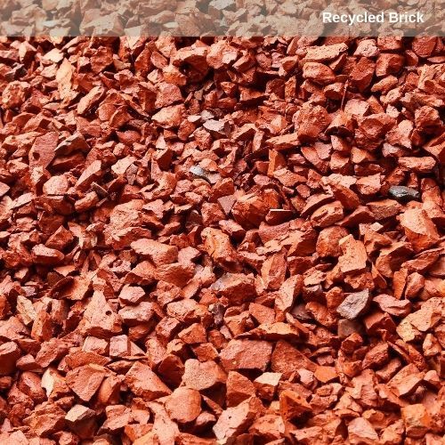 A pile of bricks and rocks in a field with trees in the background.