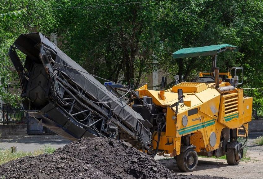 A large machine is sitting on top of a dirt field.