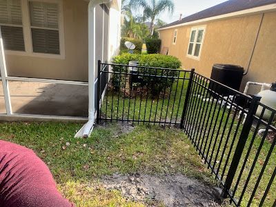 A black fence is in the backyard of a house.