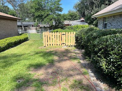 A wooden fence is sitting in the middle of a lush green yard next to a house.