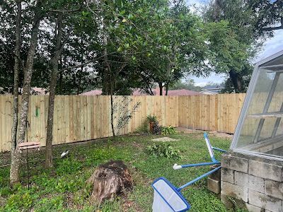 A backyard with a wooden fence and a greenhouse.