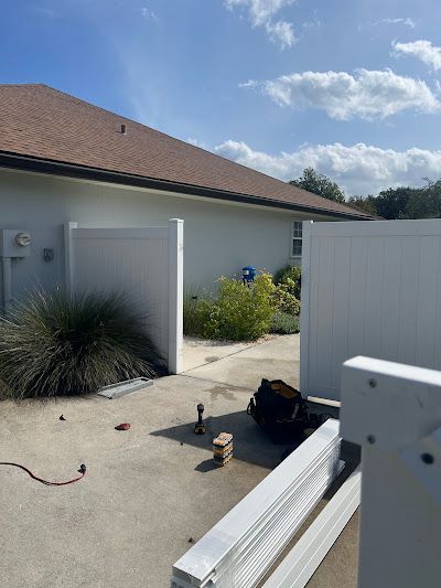 A white fence is being installed in front of a house