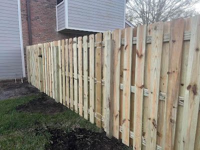 A wooden fence is sitting in the grass in front of a building.