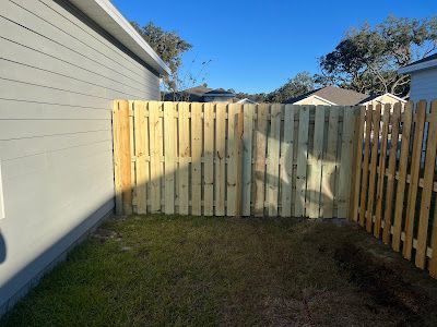 A wooden fence is in the backyard of a house.