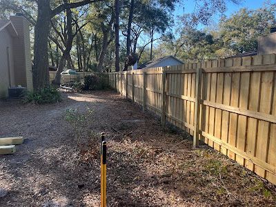 A wooden fence is being built in the backyard of a house.