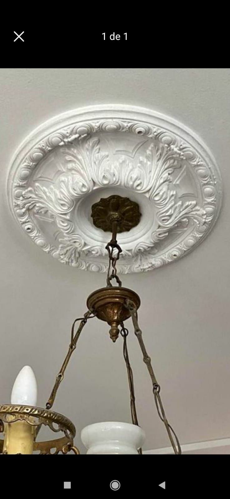 Un medallón de techo blanco con molduras ornamentadas, que sostiene una lámpara de araña de latón con pantalla blanca.