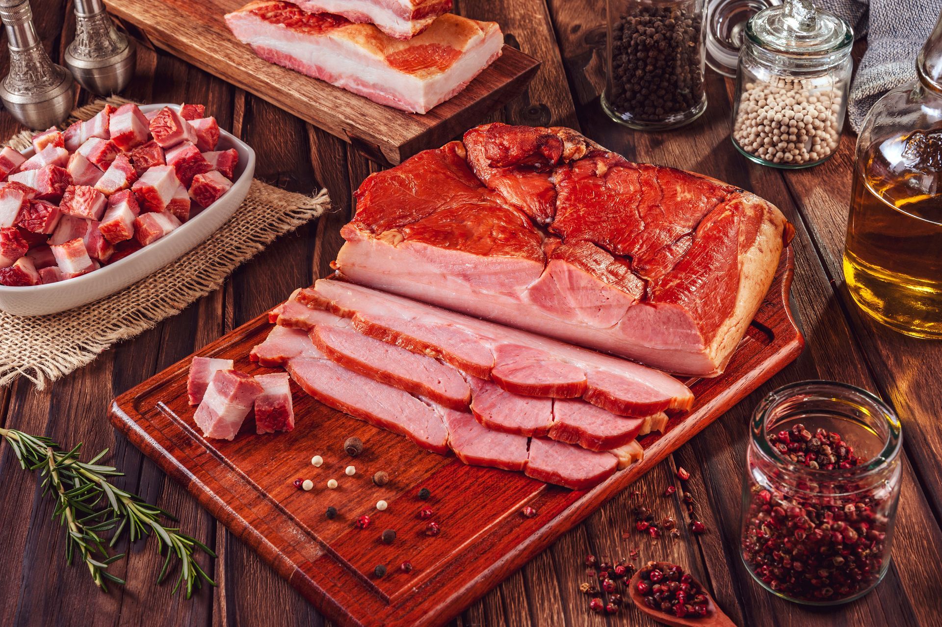 A piece of meat is sitting on a cutting board next to peppers and tomatoes.