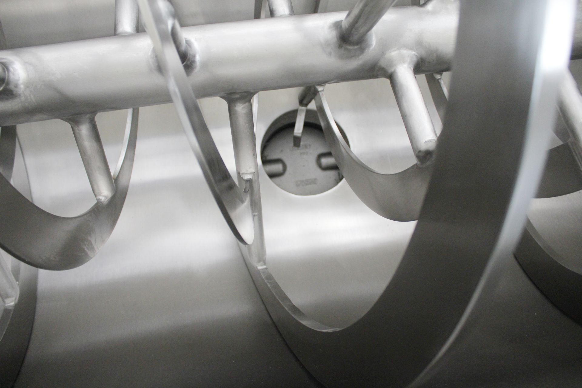 A close up of a stainless steel mixer with a hole in the middle.