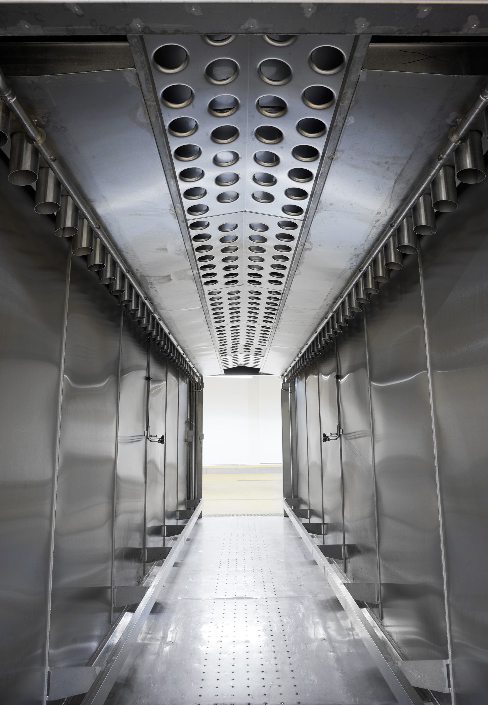 A long stainless steel hallway with holes in the ceiling