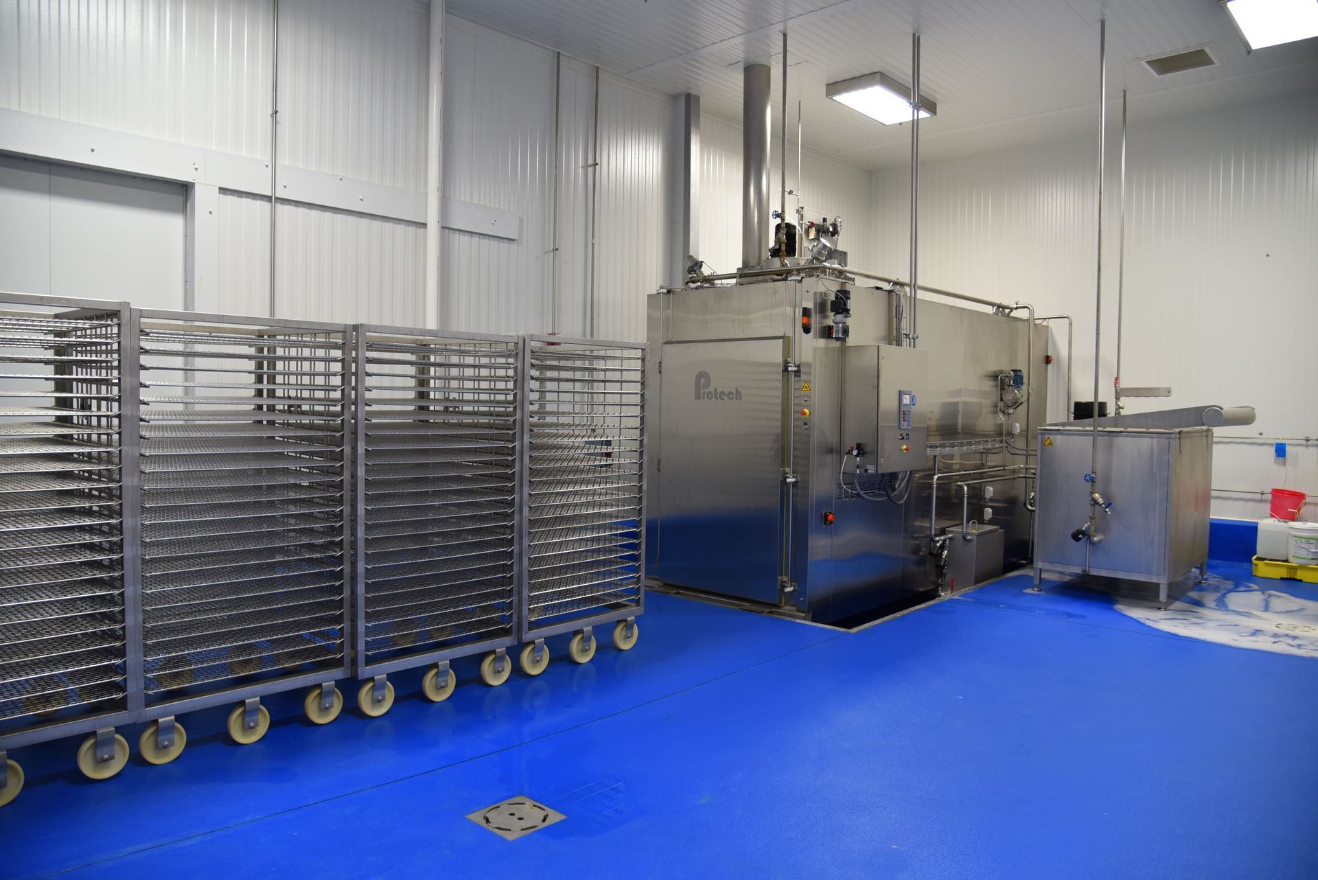 A large stainless steel machine is sitting in a room with a blue floor.