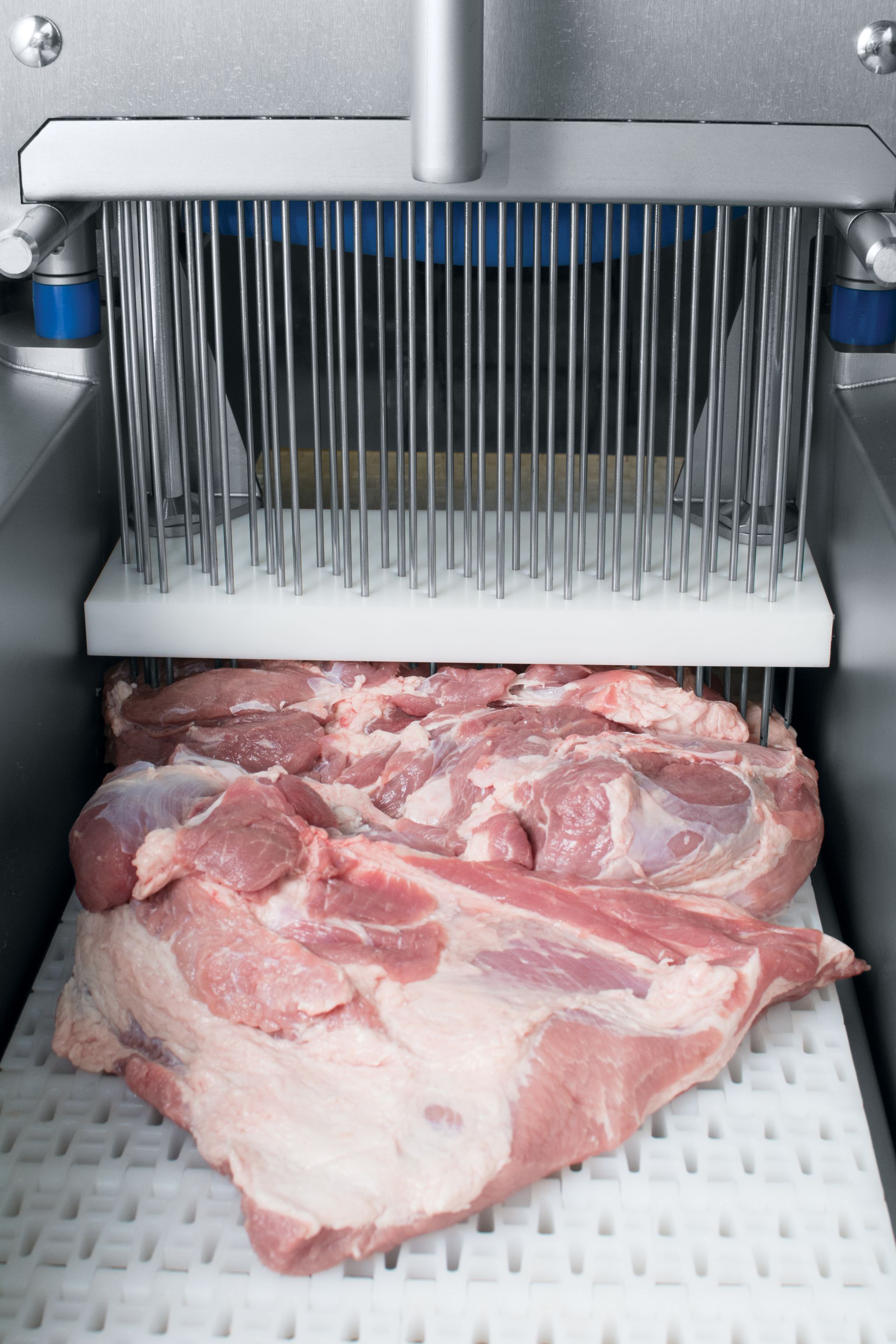 A piece of meat is being processed in a machine.