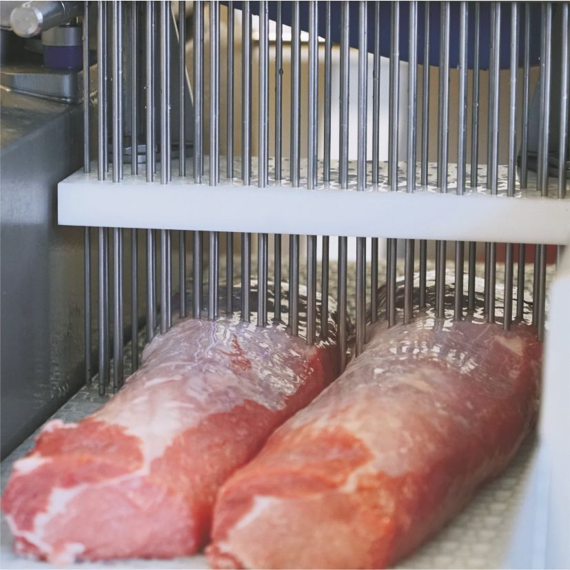 Two pieces of meat are being processed in a machine