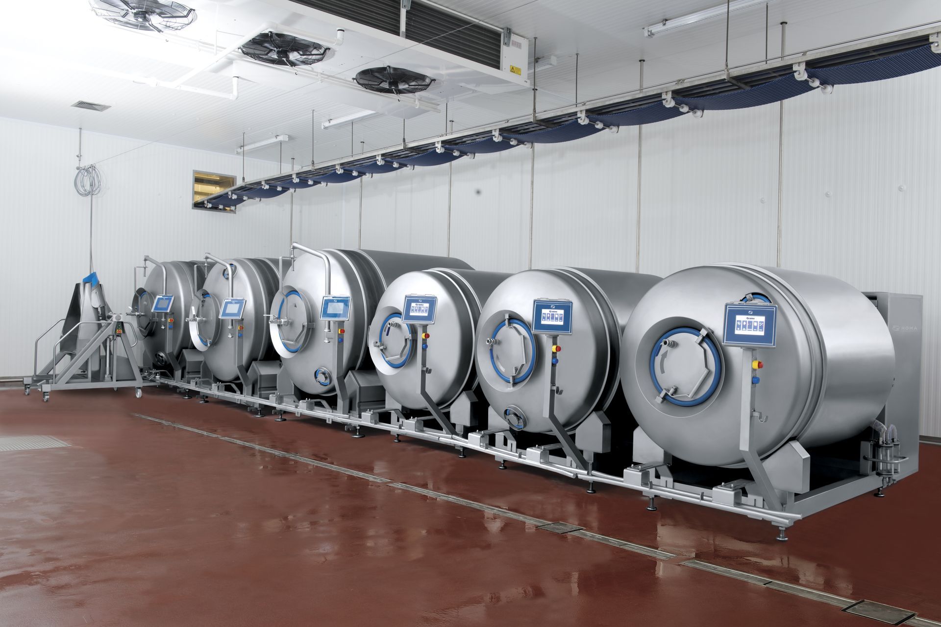 A row of stainless steel tanks are lined up in a room.