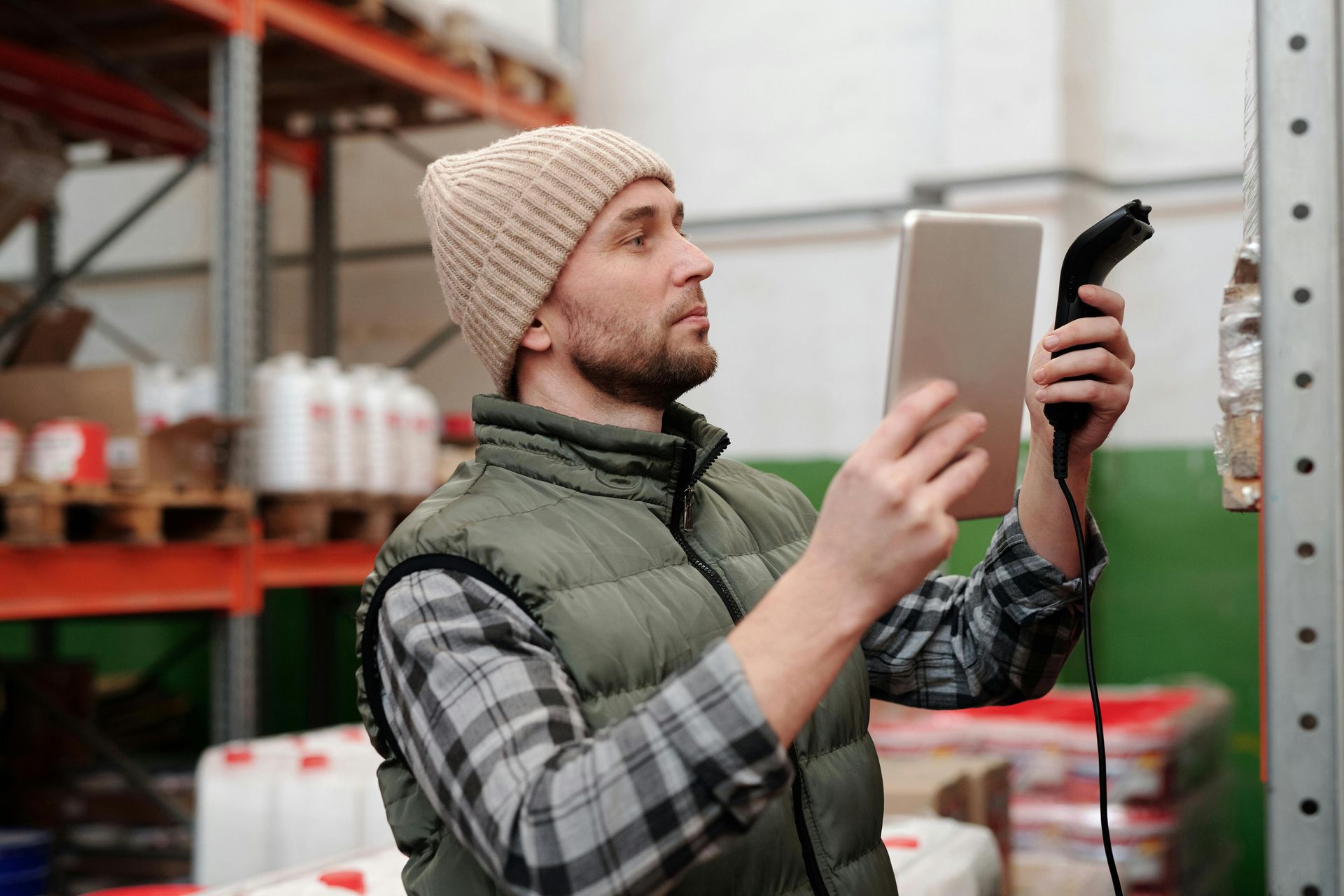A man is using a tablet and a scanner in a warehouse.