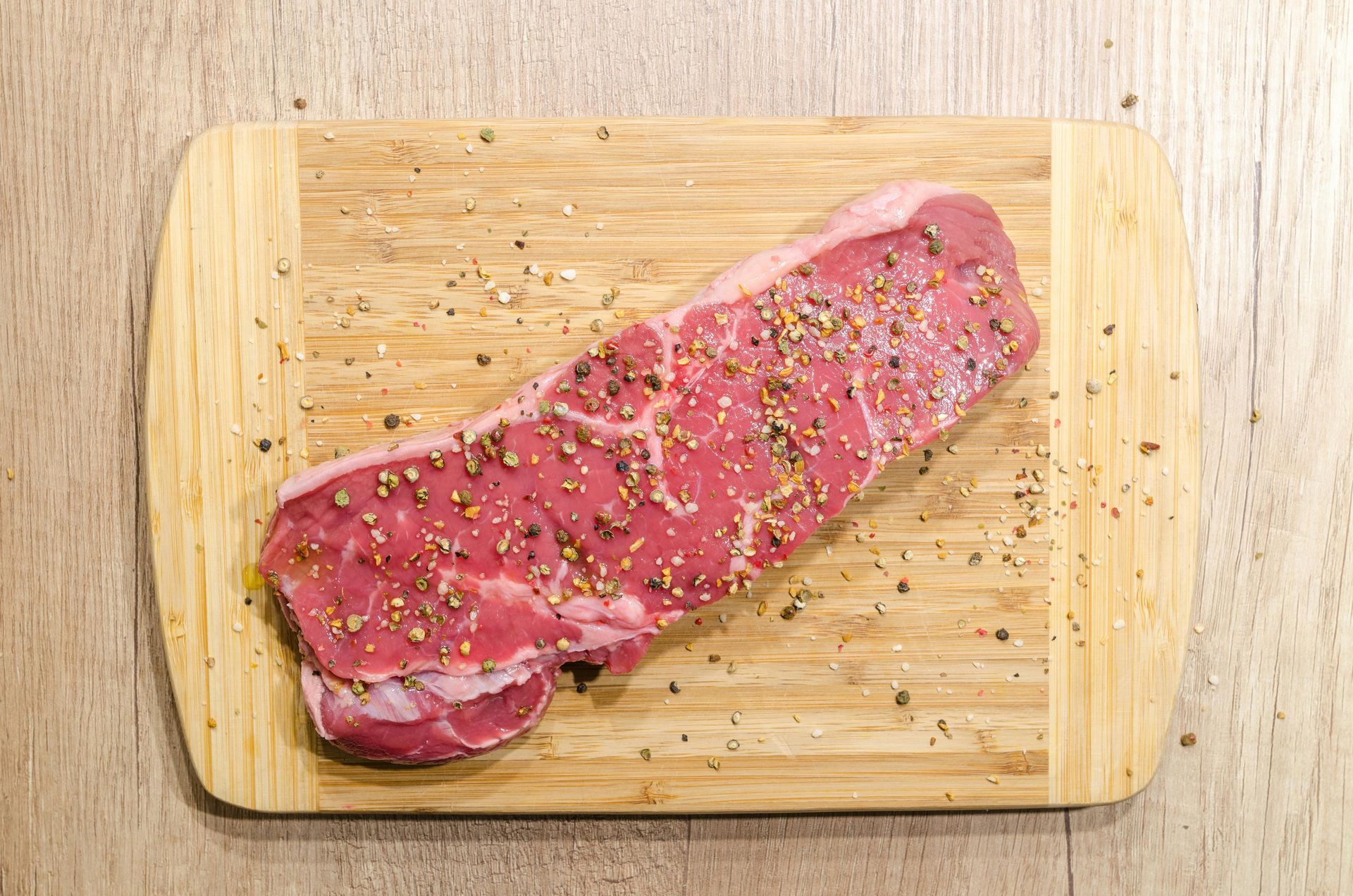 A piece of raw steak on a wooden cutting board.