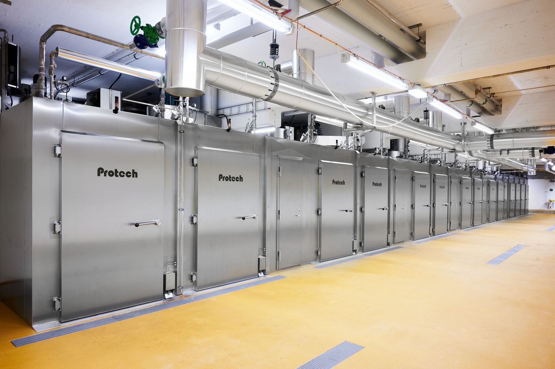 A row of stainless steel doors are lined up in a room.