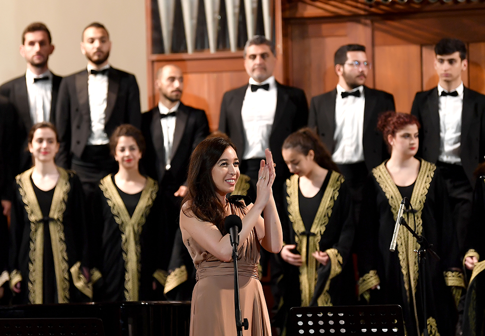 Lynn Zovighian welcomes the Fayha National Choir on stage at the inaugural concert of “Giving Voice to Music.”