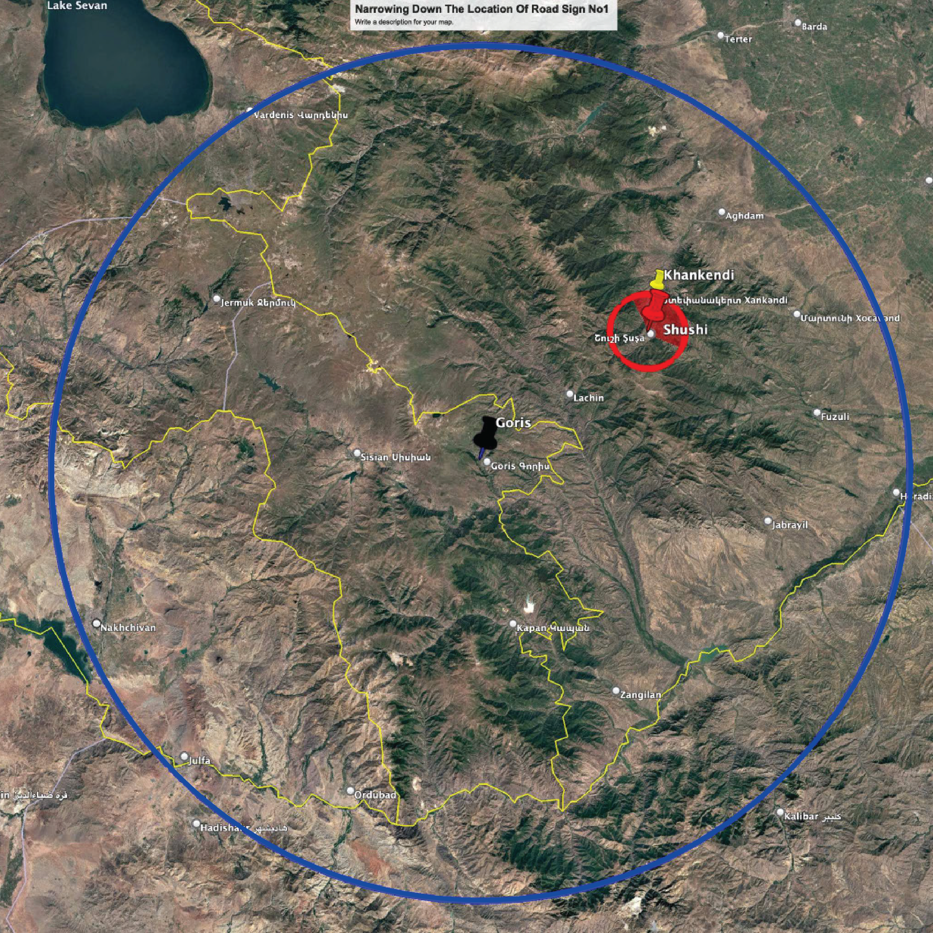 Overhead view, circular map with a blue and red circle, marking a location. Terrain is mountainous with some roads visible.
