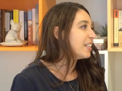 Lynn Zovighian portrait image looking to the right, sitting in front of a book shelf