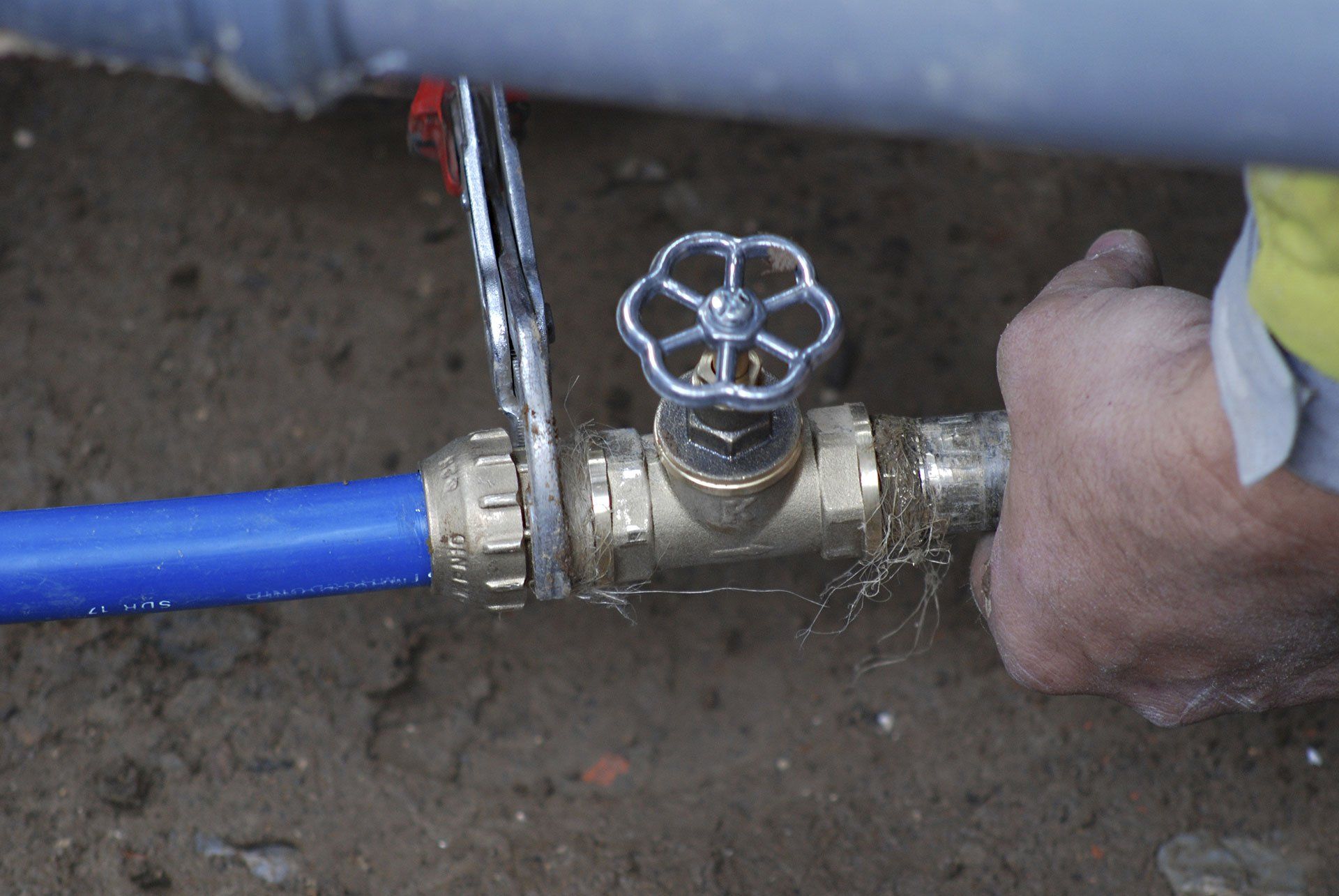a person is using a wrench to open a valve on a blue pipe