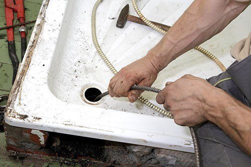 A plumber performing drain cleaning services