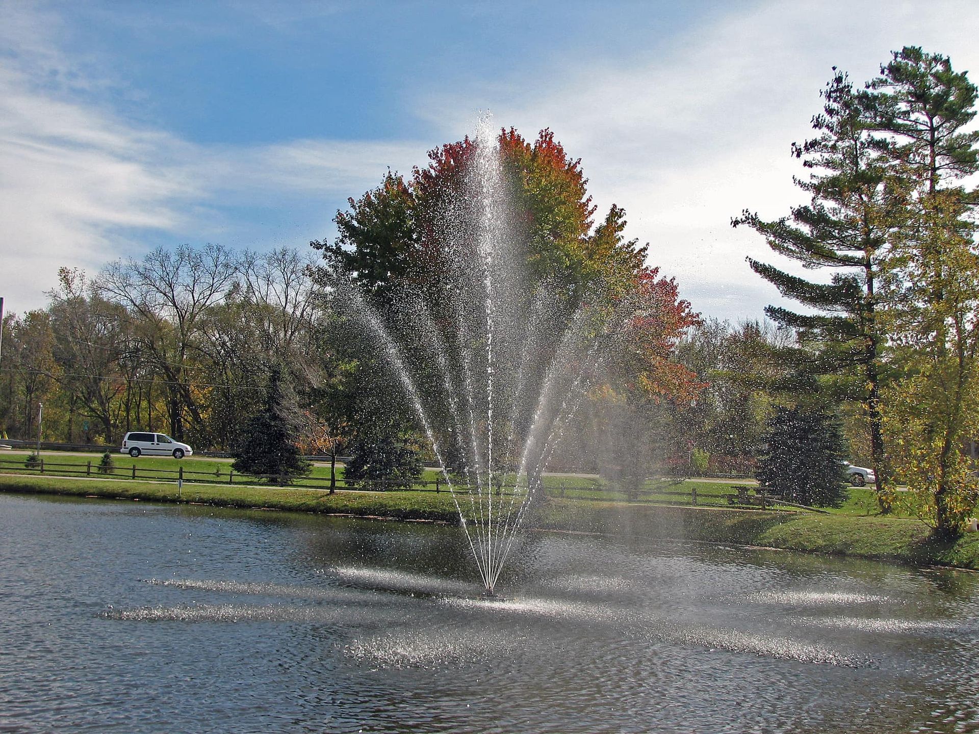 A fountain is spraying water over a lake in a park