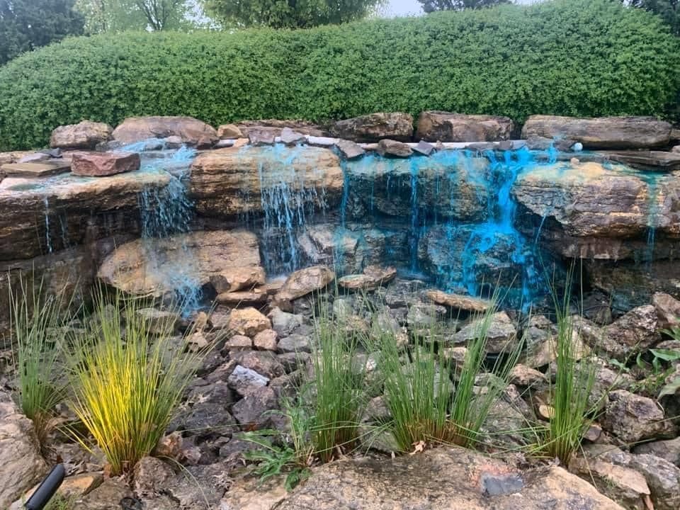 A waterfall is surrounded by rocks and plants in a garden.