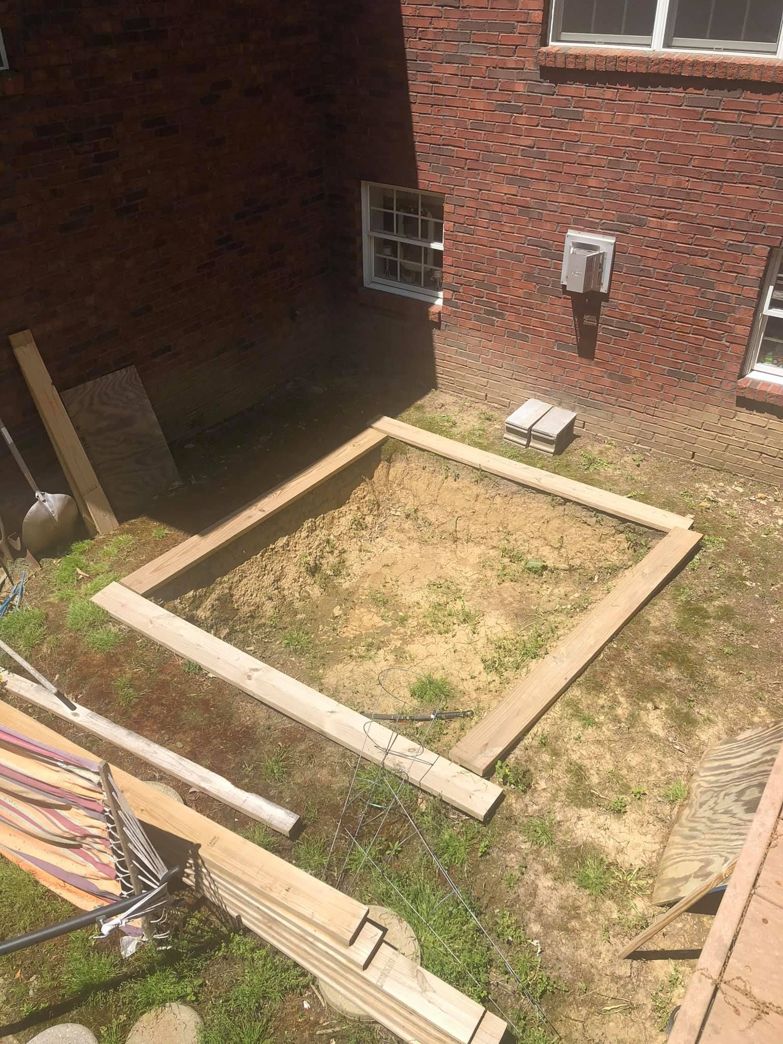 A wooden box is sitting in the grass in front of a brick building.