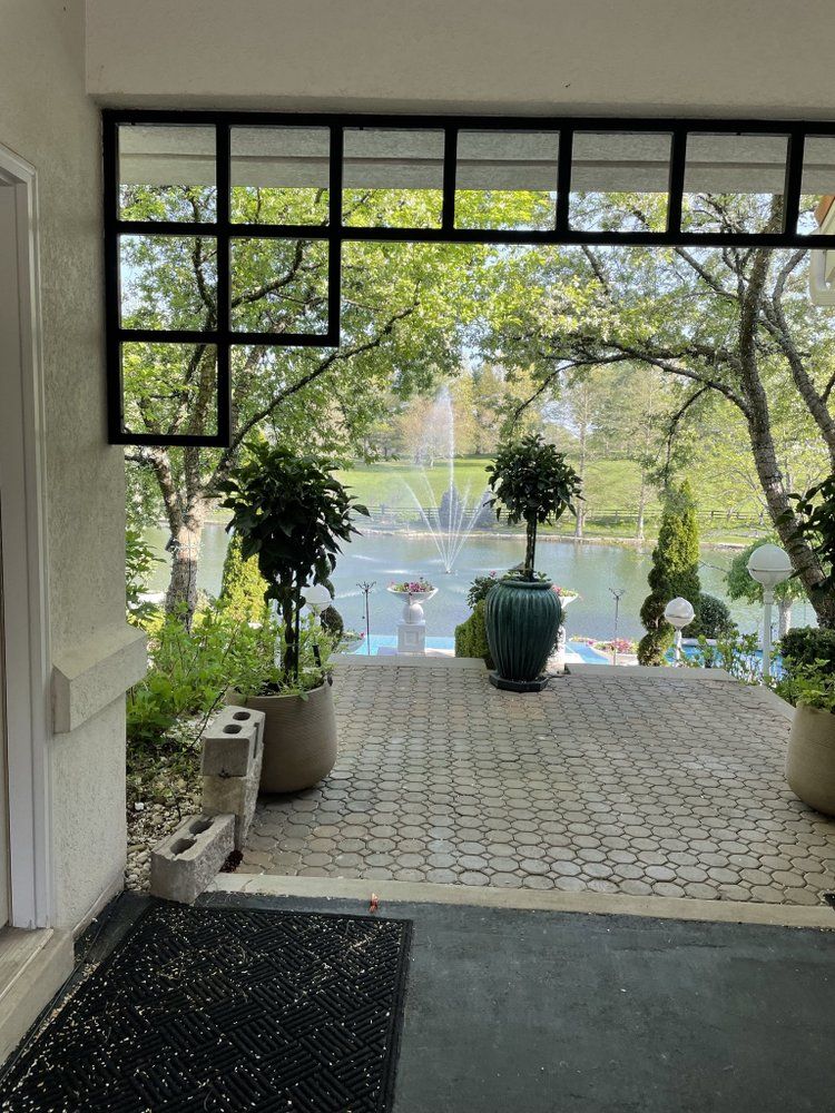 A patio with potted plants and a fountain in the background.