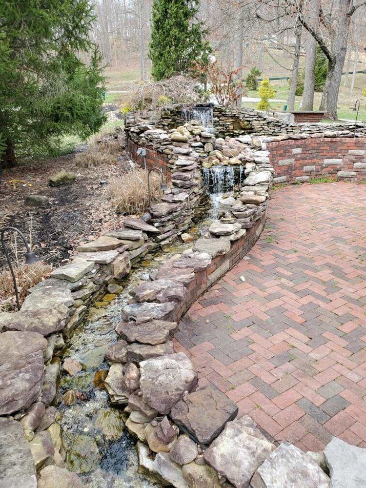 A waterfall is surrounded by rocks and bricks in a garden.