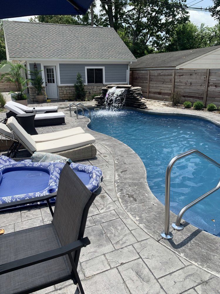 A large swimming pool with a waterfall in the backyard of a house