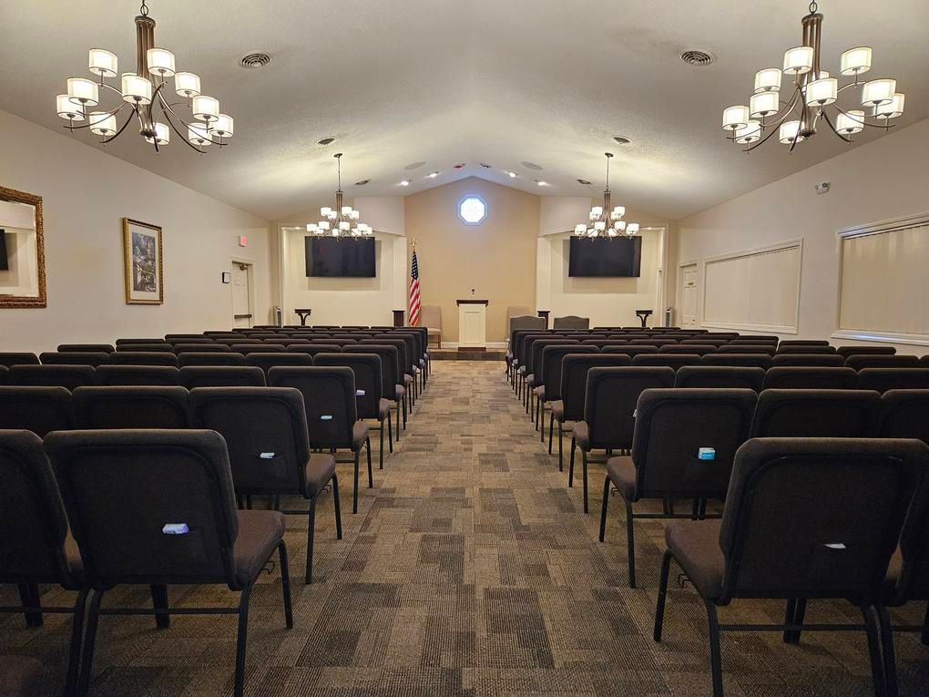 Rows of black chairs face a podium in a light-filled auditorium.