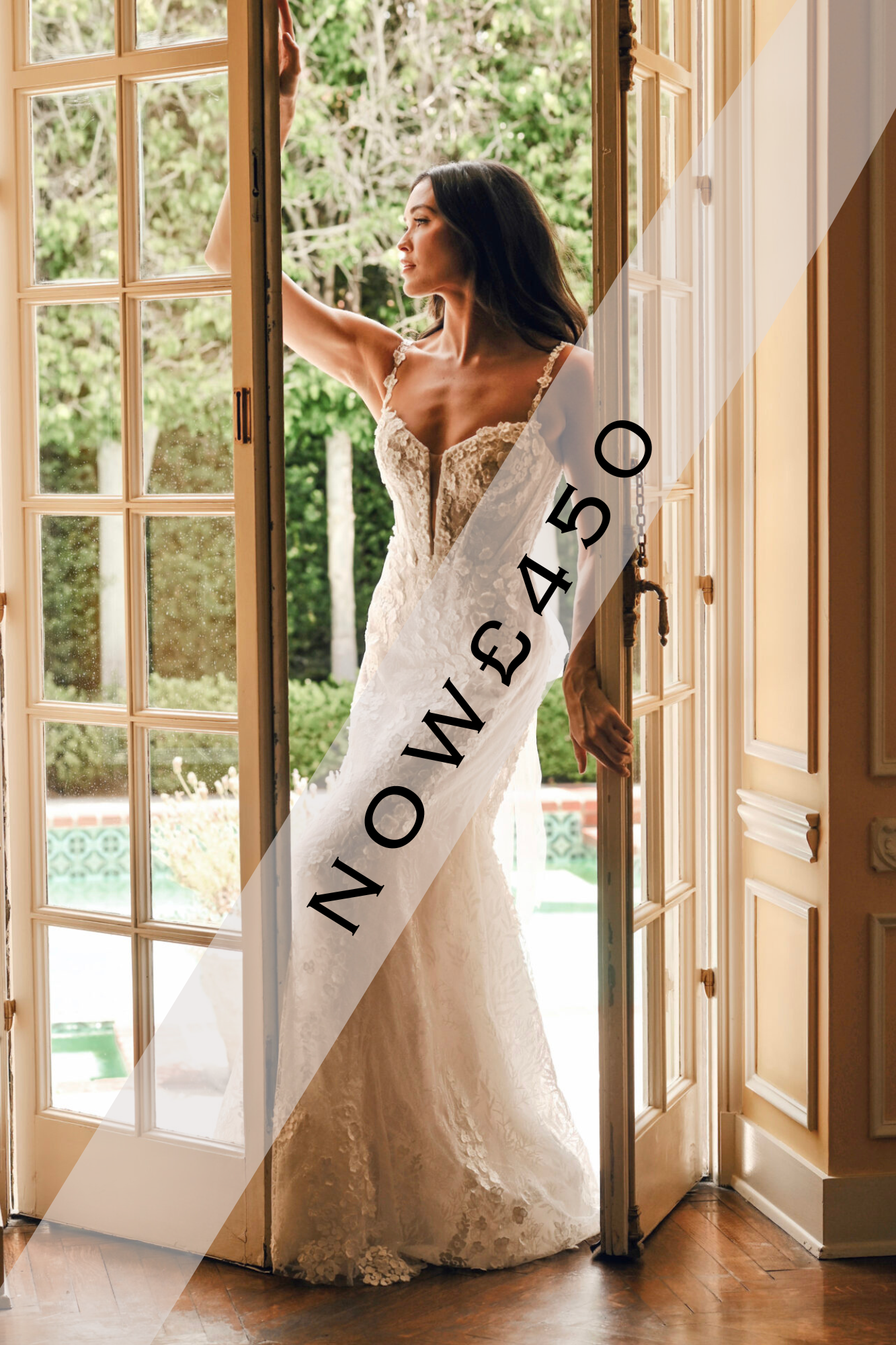 Lady stood in lace, fitted, Ivory wedding dress by Martina Liana. It has lace detailing running throughout the gown, thin straps and exposed boning.