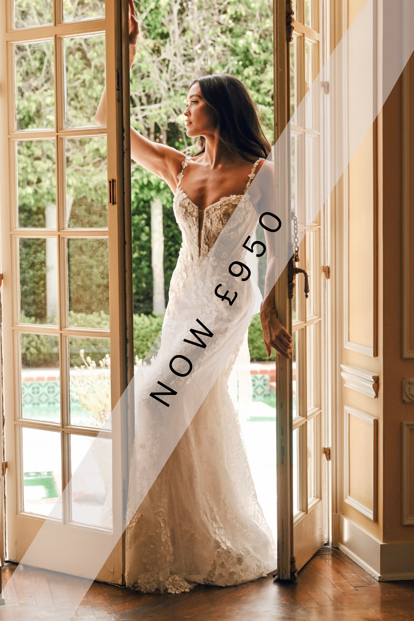 Lady stood in lace, fitted, Ivory wedding dress by Martina Liana. It has lace detailing running throughout the gown, thin straps and exposed boning.