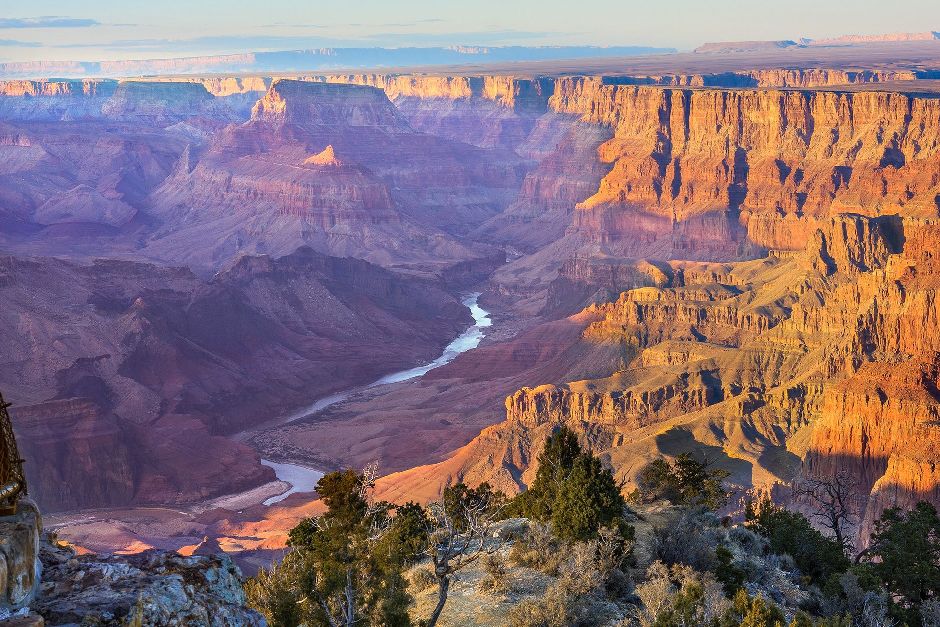 A person is standing on top of a rocky hill at sunset.