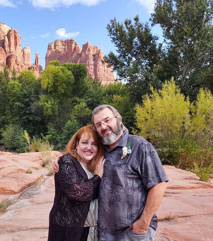 A man and a woman are posing for a picture in front of a mountain.